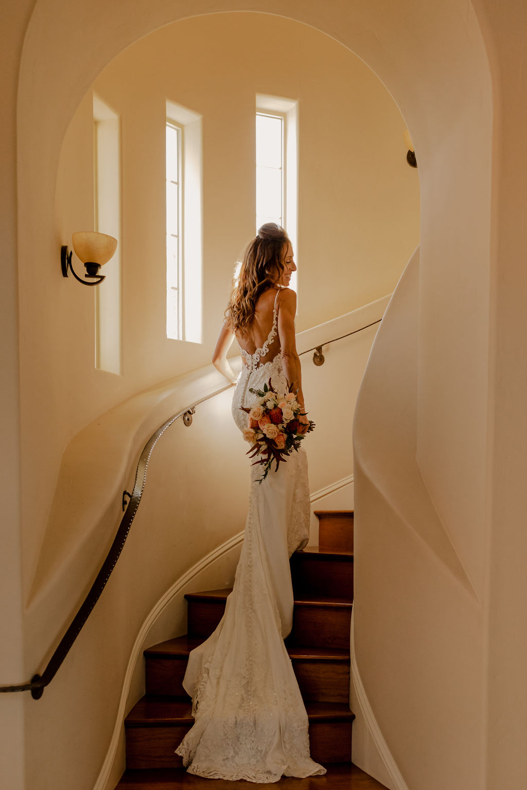 bridal portraits of bride in open back wedding dress walking up stairs