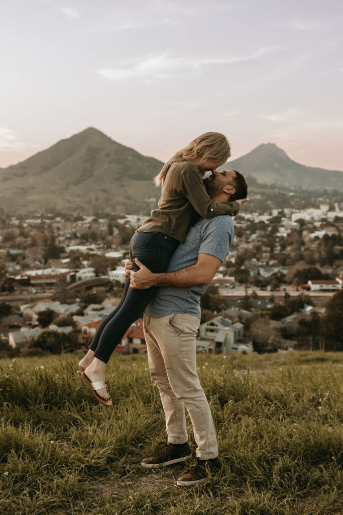 couple hugging on hill at engagement session