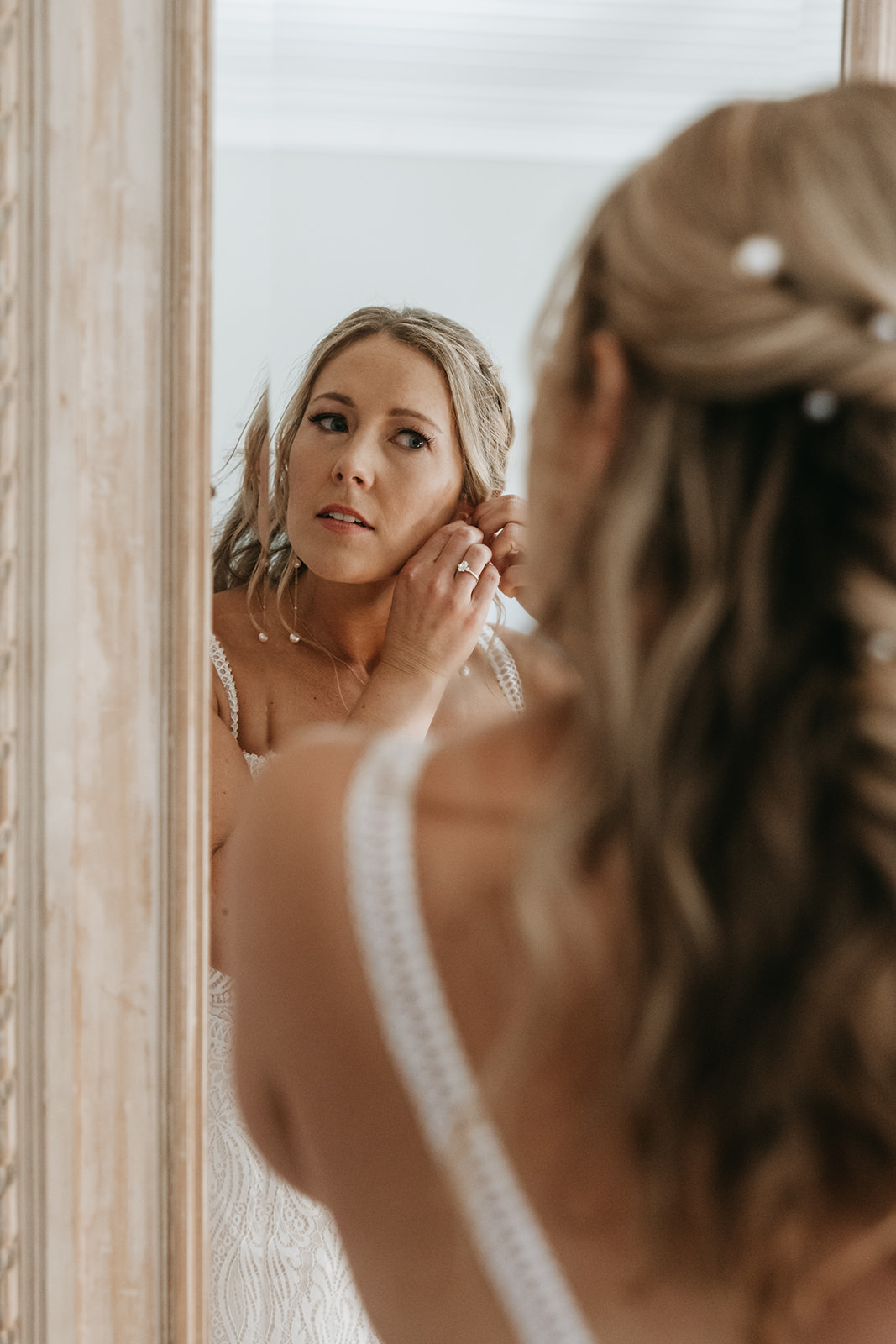 bride putting in her earrings in the mirror | The Penny: A Downtown Wedding Venue in San Luis Obispo