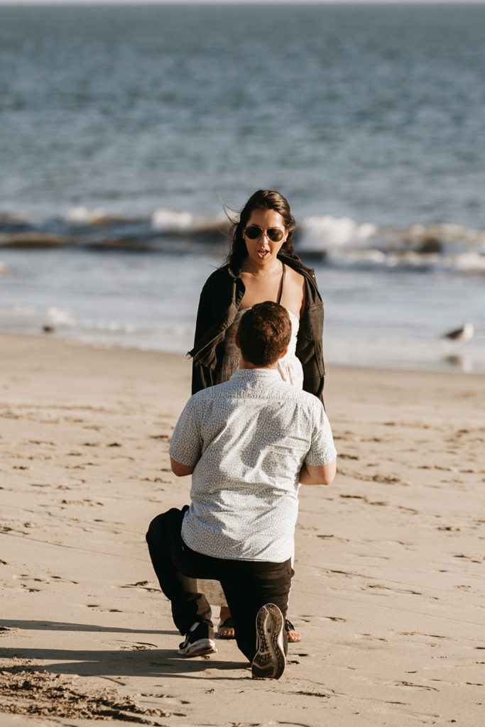 couple walking and posing on the beach after their engagement

