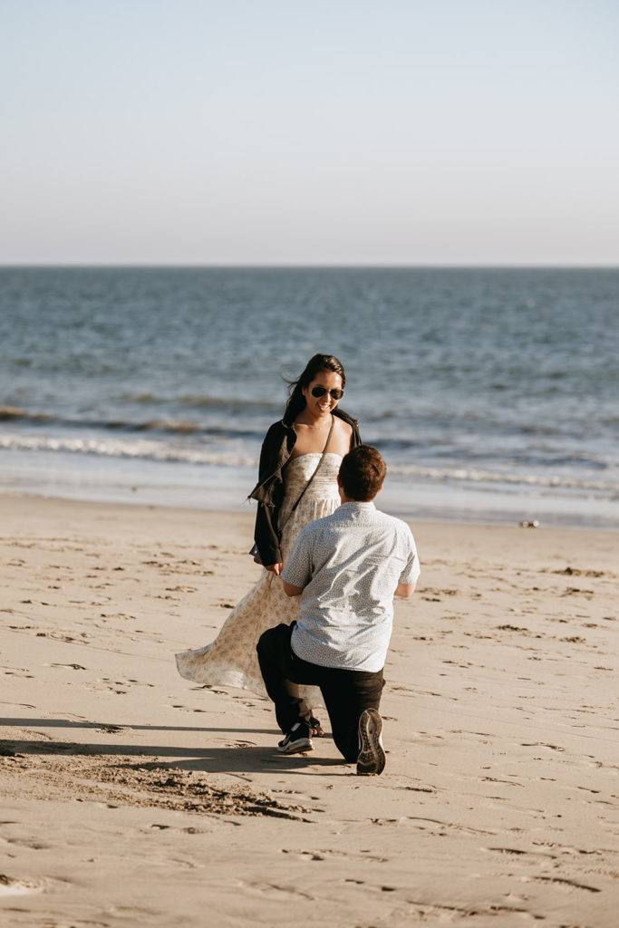 couple walking and posing on the beach after their engagement

