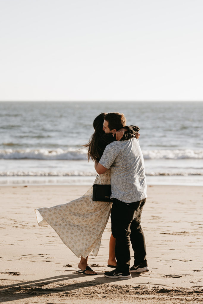 couple walking and posing on the beach after their engagement
