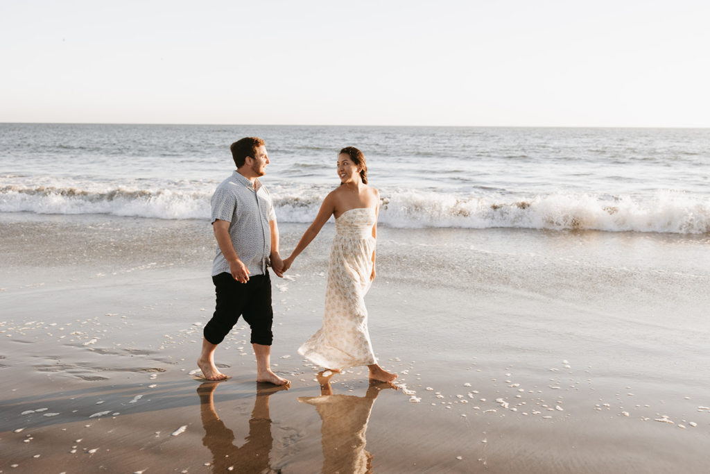couple walking and posing on the beach after their engagement 