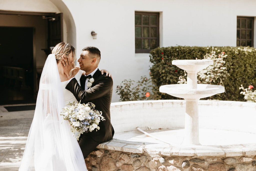 bride and groom posing at san luis obispo mission for their wedding photos
