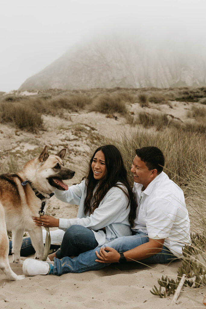 couple posing with their dog on a beach for their photoshoot