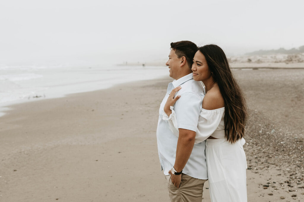 a couple posing for a romantic moody photoshoot on the beach to celebrate their engagement
