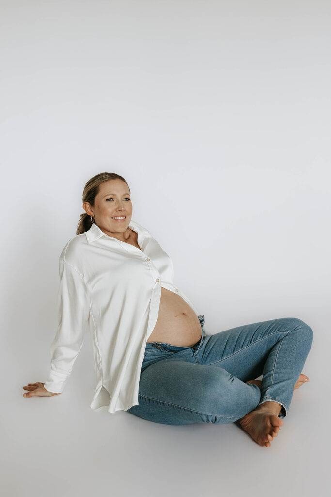 couple posing in a studio for a maternity milestone picture photoshoot
