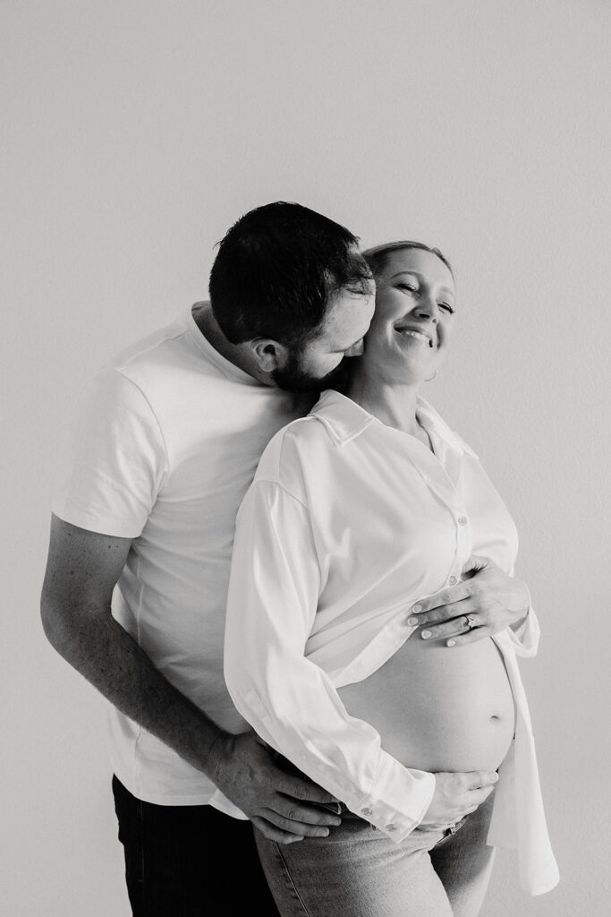 couple posing in a studio for a maternity milestone picture photoshoot
