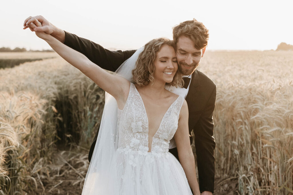 couple posing in a field for their wedding portraits