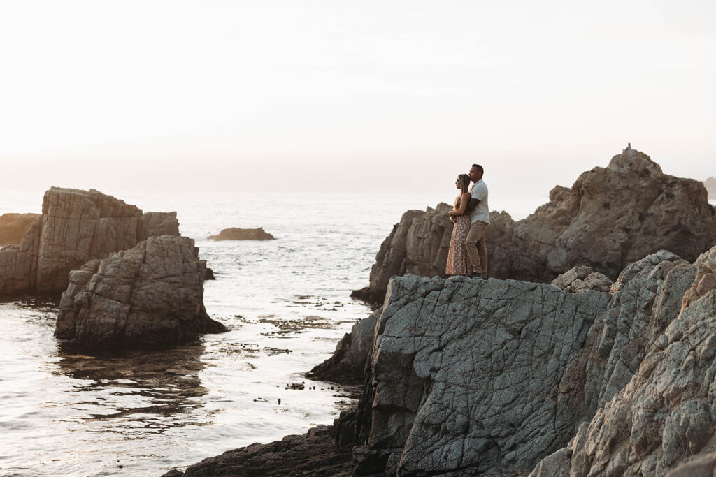 a newly engaged couple posing for their picture in the cliffs of big sur
