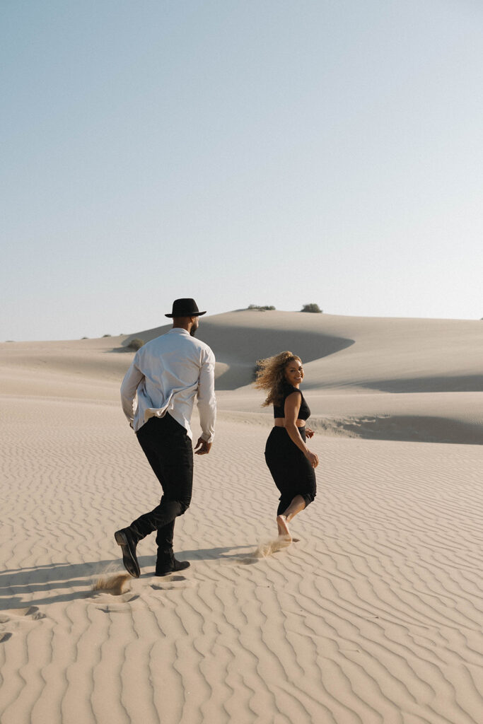 couple posing near pismo beach sand dunes and the pier for their engagement photos
