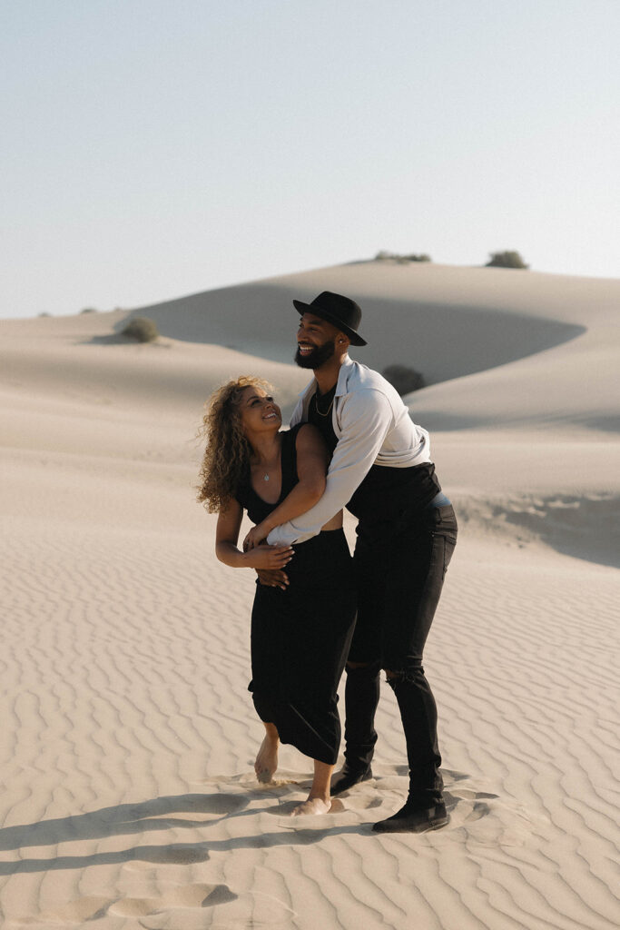 couple posing on the beach and sand dunes for an engagement session
