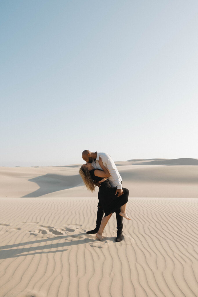 couple posing on the beach and sand dunes for an engagement session
