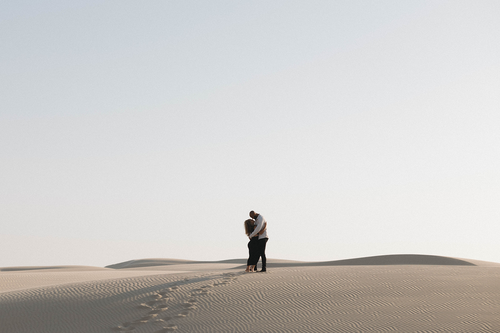 couple posing near pismo beach sand dunes and the pier for their engagement photos