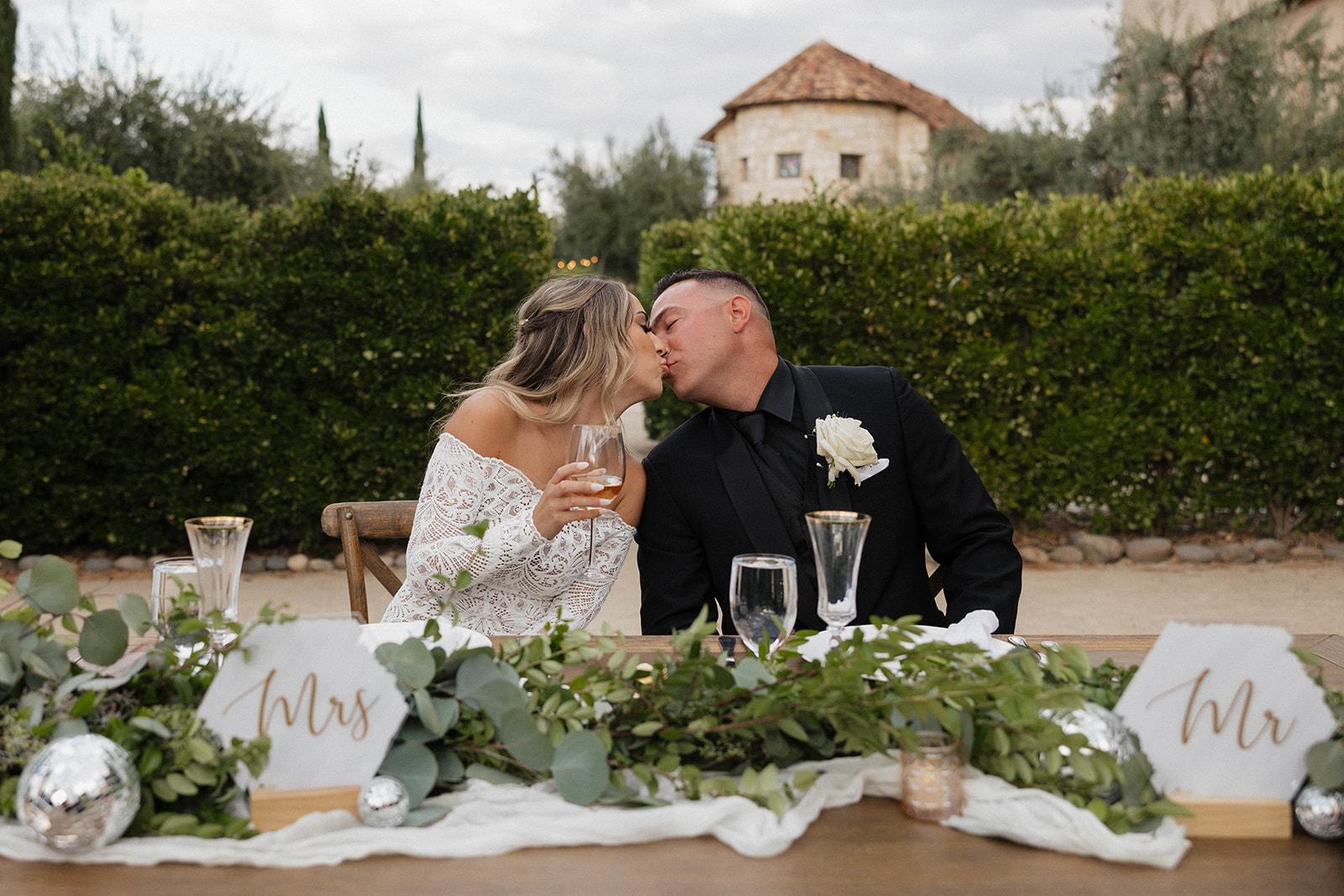 bride and groom kissing during dinner at their wedding reception